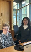 Mitarbeitende mit und ohne Behinderung sitzen freundlich blickend hinter dem Empfangstresen.