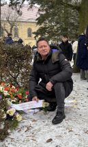 Bürgermeister Steffen Apelt kniet vor niedergelegten Kränzen.