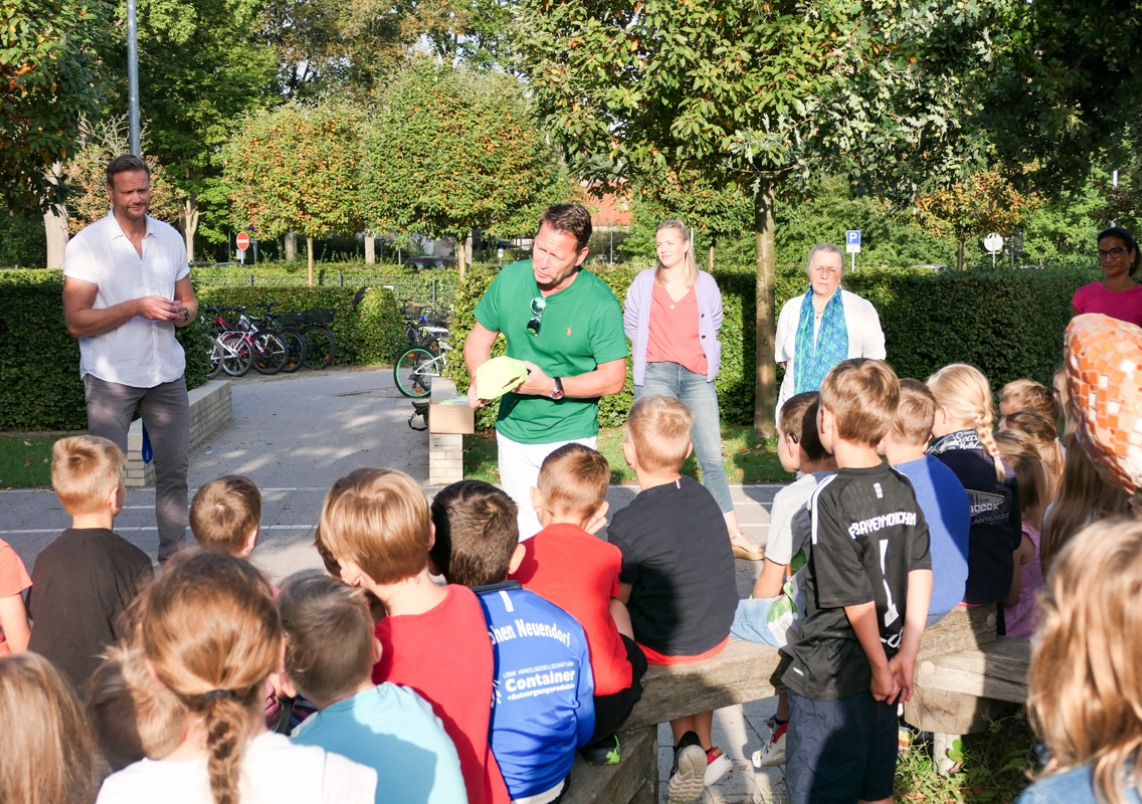 Bürgermeister Steffen Apelt verteilt reflektierende Mützen an Erstklässler der Grundschule Niederheide.