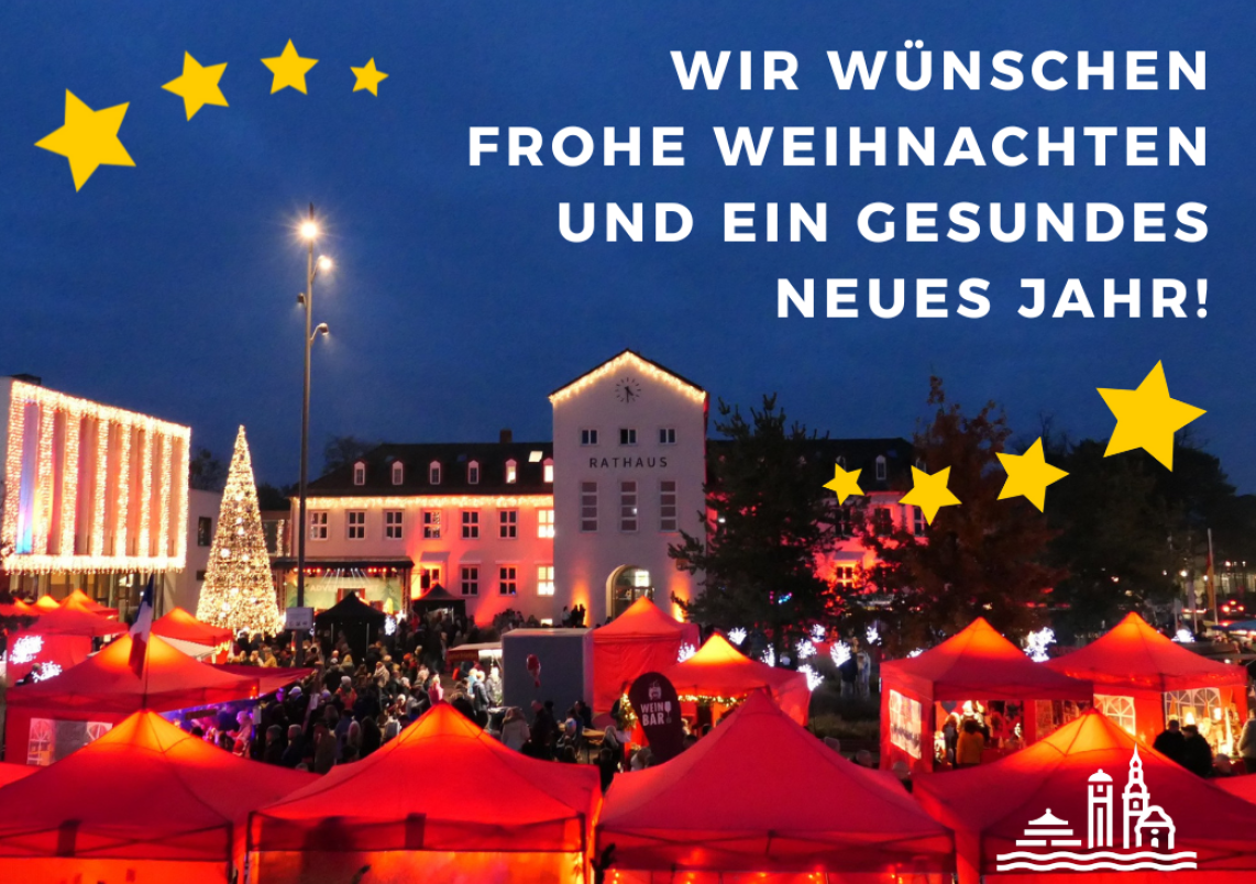 Rot leuchtende Adventsmarkt-Stände auf dem Rathausplatz, mit Schrift "Wir wünschen Ihnen frohe Weihnachten und ein gesundes neues Jahr"