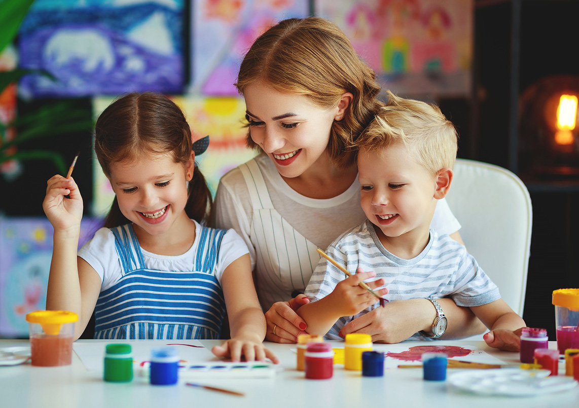 Erwachsene Person mit Kindern beim Malen